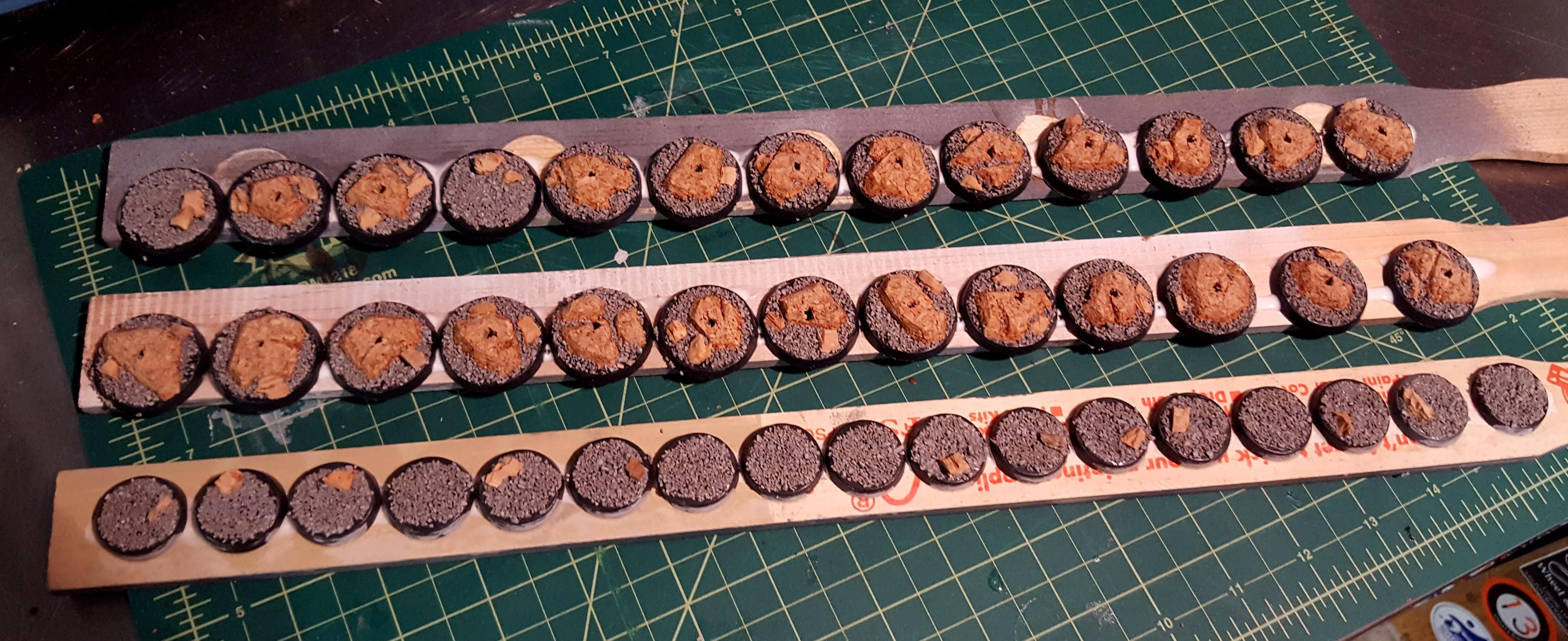 Three batches of bases, textured, mounted, and ready to paint in bulk